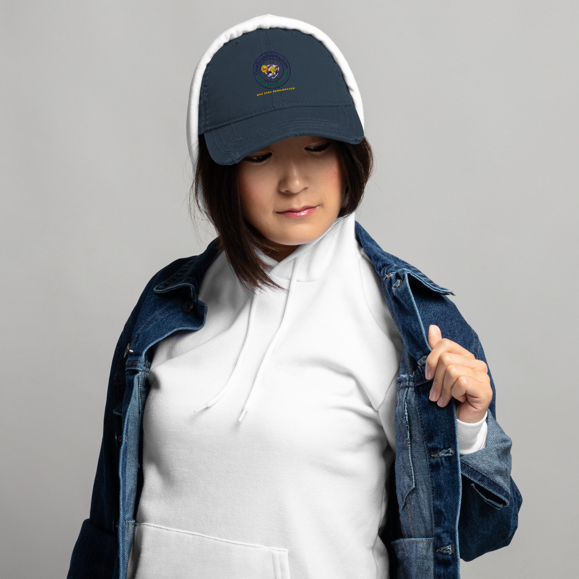 Woman wearing a white hoodie and a blue cap.