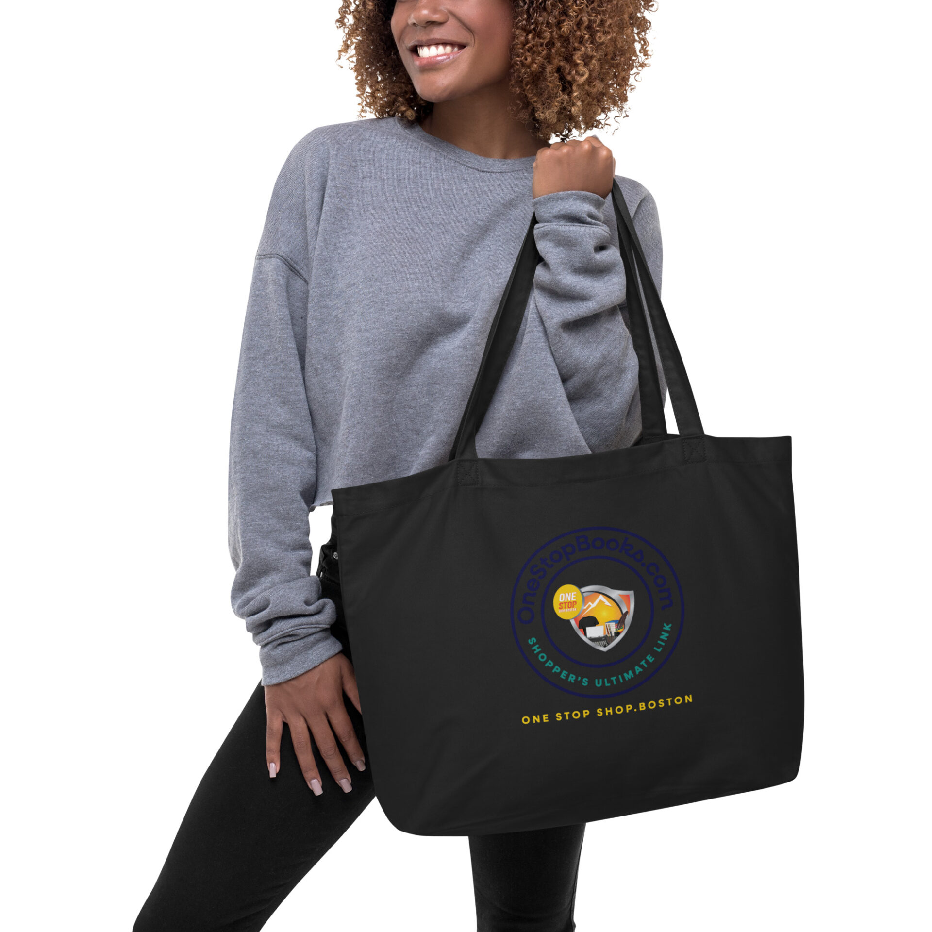 Woman holding black tote bag with logo.