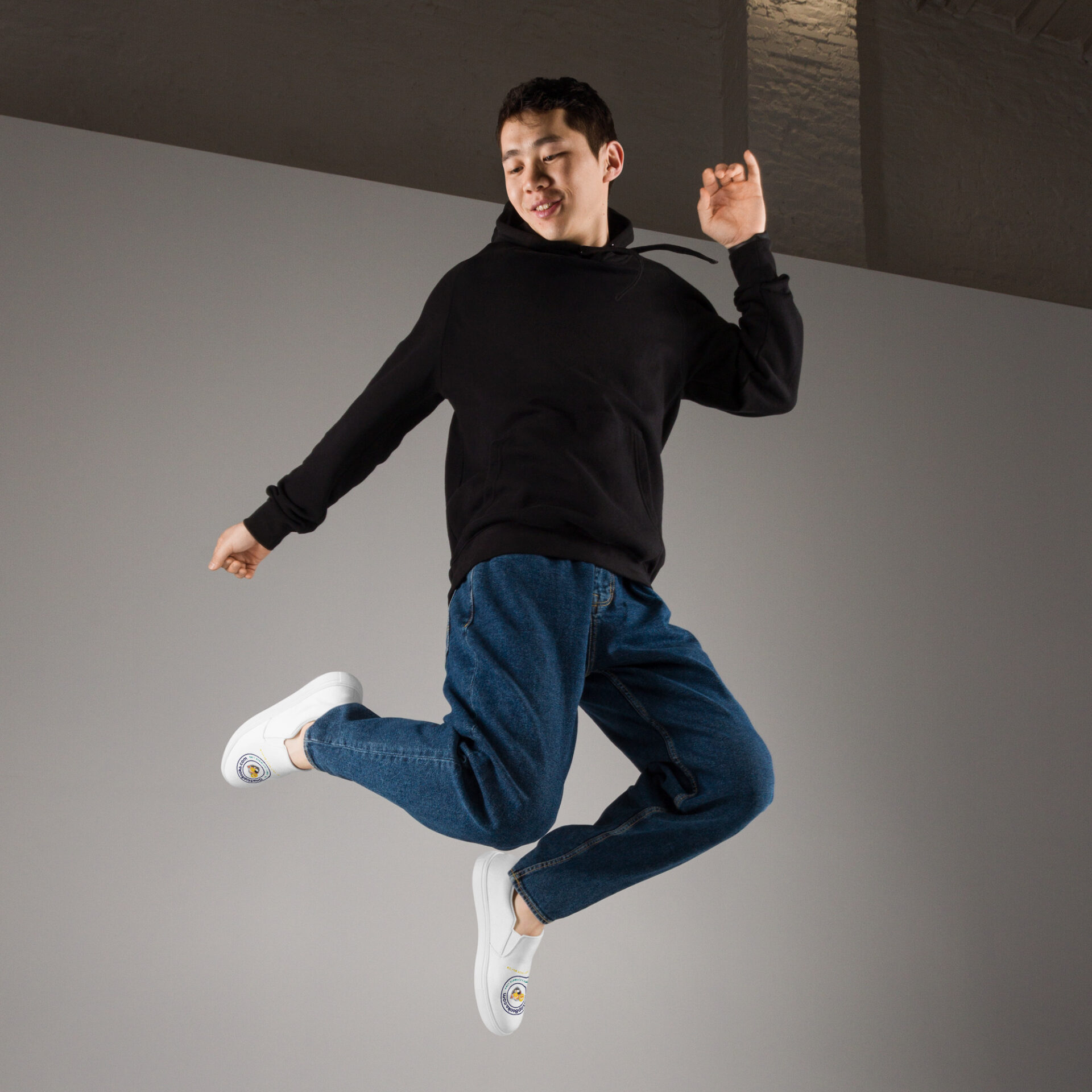 Man in black hoodie jumps with sneakers on.